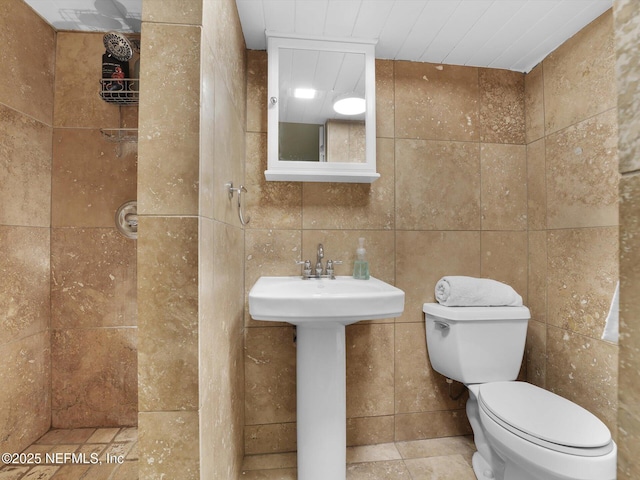 bathroom with toilet, tile walls, and sink