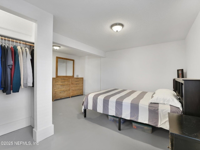 bedroom with a textured ceiling, concrete flooring, and a closet