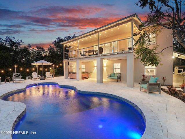 pool at dusk featuring a jacuzzi, an outdoor hangout area, and a patio area