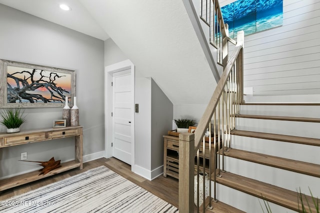 stairs featuring baseboards, vaulted ceiling, wood finished floors, and recessed lighting