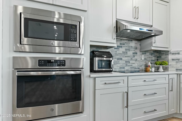 kitchen with stainless steel appliances, extractor fan, white cabinetry, and decorative backsplash