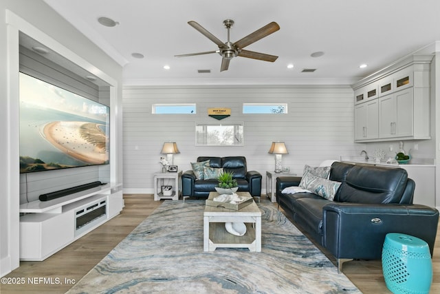 living room with hardwood / wood-style floors, ornamental molding, and ceiling fan