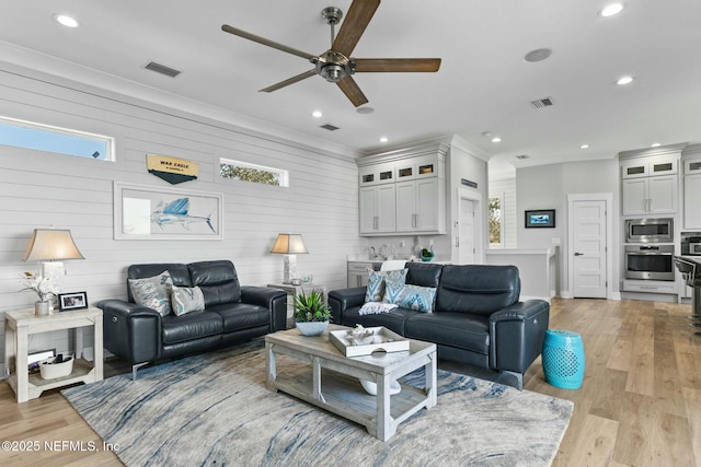 living room featuring ornamental molding, a healthy amount of sunlight, ceiling fan, and light hardwood / wood-style flooring