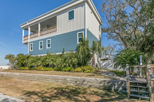 view of side of home featuring a balcony, board and batten siding, and a yard