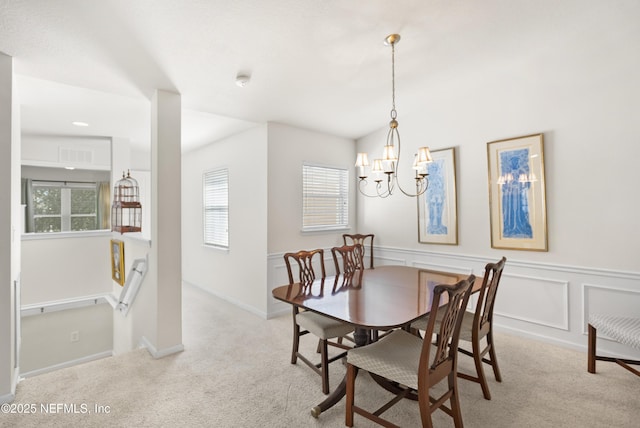 dining space with a notable chandelier, a decorative wall, carpet flooring, visible vents, and wainscoting