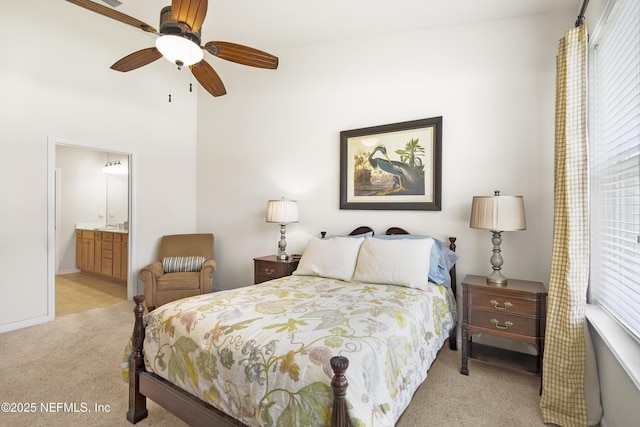 bedroom featuring light carpet, ensuite bath, and a ceiling fan