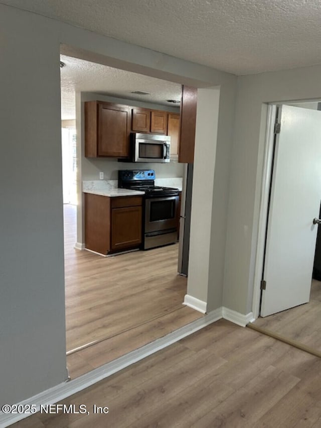 kitchen featuring light hardwood / wood-style floors, a textured ceiling, and appliances with stainless steel finishes