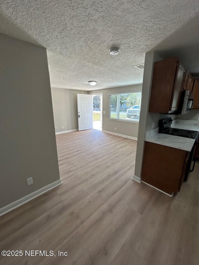 kitchen featuring a textured ceiling, light wood-type flooring, and range with electric stovetop