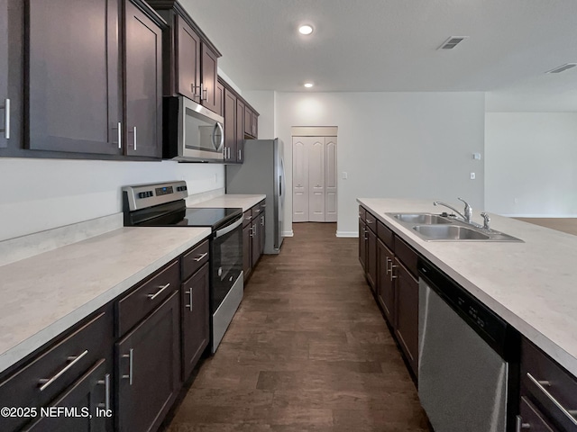 kitchen with dark brown cabinets, sink, stainless steel appliances, and dark wood-type flooring