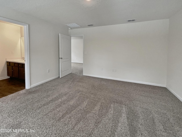 unfurnished room featuring a textured ceiling and dark carpet