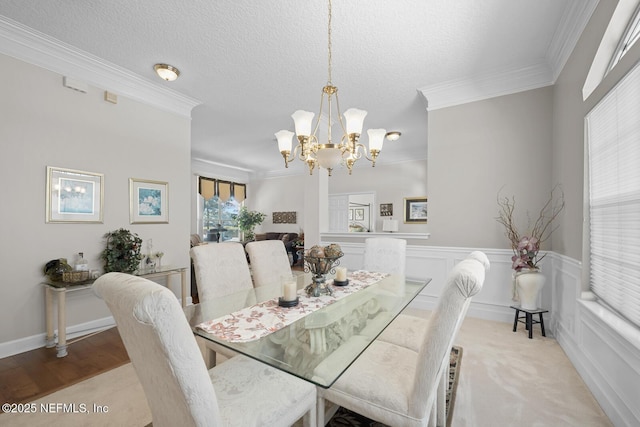 carpeted dining room with a textured ceiling, crown molding, and a notable chandelier