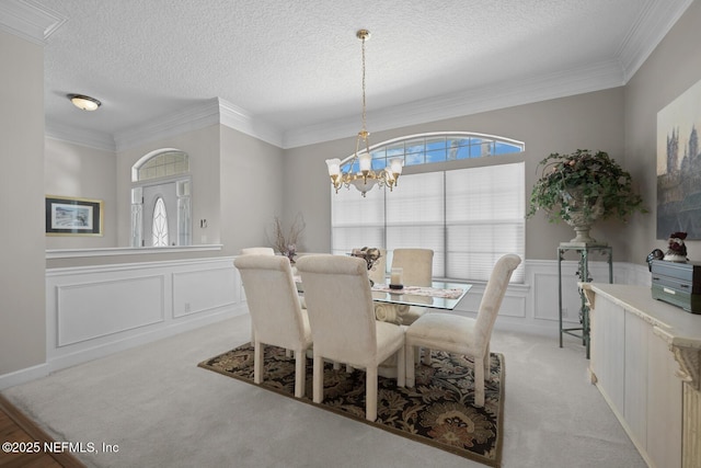 carpeted dining room with ornamental molding, a textured ceiling, and a notable chandelier