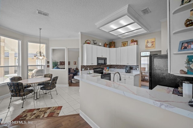 kitchen with white cabinets, black appliances, hanging light fixtures, light tile patterned floors, and ornamental molding