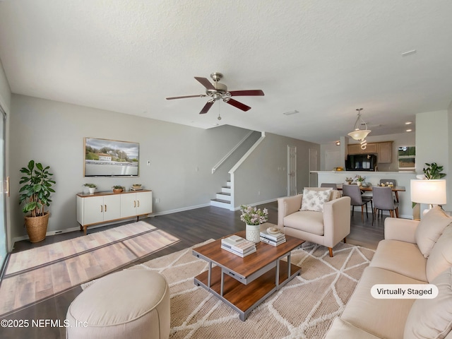 living room with hardwood / wood-style flooring, ceiling fan, and a textured ceiling