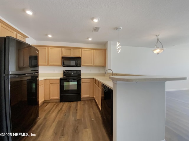 kitchen featuring kitchen peninsula, light brown cabinetry, sink, black appliances, and pendant lighting