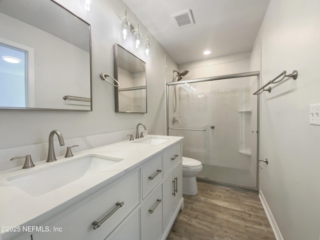 bathroom featuring hardwood / wood-style flooring, toilet, vanity, and walk in shower