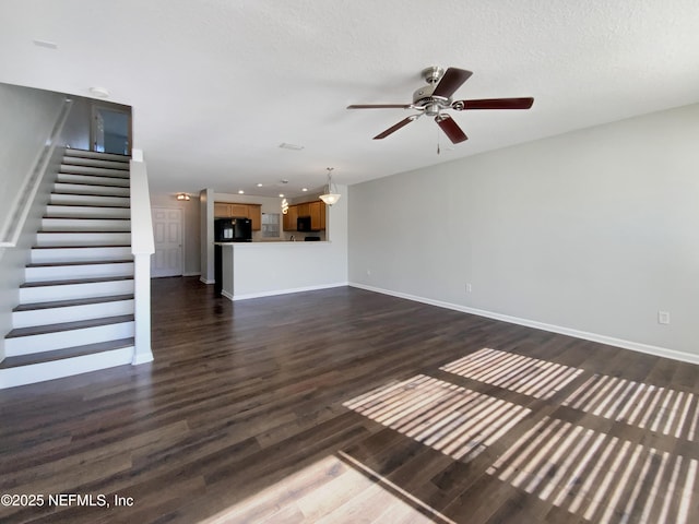 unfurnished living room with a textured ceiling, ceiling fan, and dark wood-type flooring