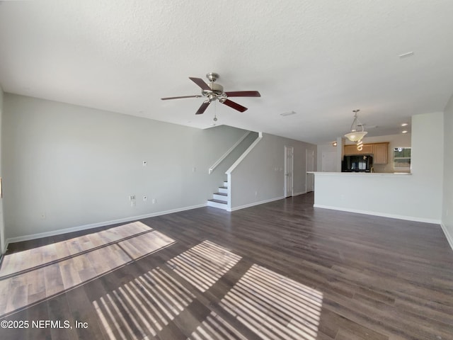 unfurnished living room featuring ceiling fan, dark hardwood / wood-style flooring, and a textured ceiling