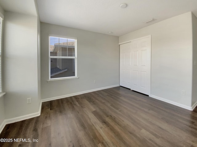 unfurnished bedroom featuring dark hardwood / wood-style flooring and a closet