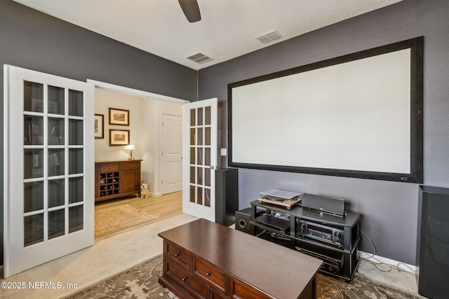 home theater room featuring carpet floors, a textured ceiling, ceiling fan, and french doors