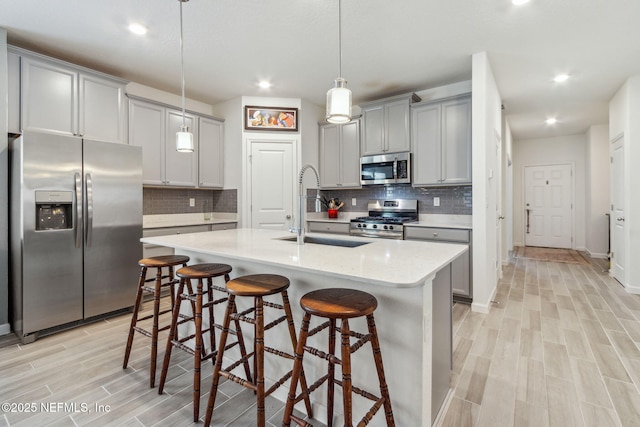 kitchen with sink, decorative light fixtures, gray cabinets, and appliances with stainless steel finishes