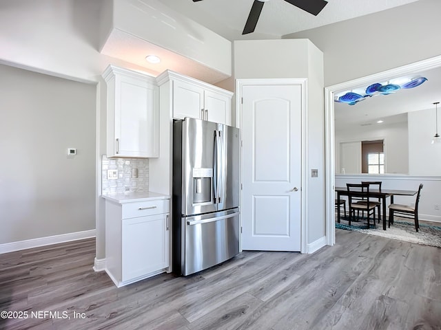 kitchen with white cabinets, tasteful backsplash, stainless steel fridge, and light hardwood / wood-style flooring