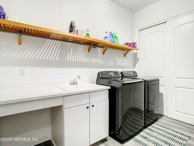 laundry area with cabinets, independent washer and dryer, light hardwood / wood-style floors, and sink