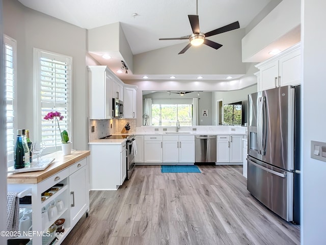 kitchen featuring lofted ceiling, sink, appliances with stainless steel finishes, white cabinetry, and decorative backsplash