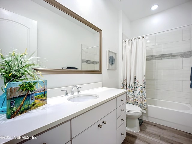 full bathroom with hardwood / wood-style flooring, shower / bath combo, vanity, and toilet