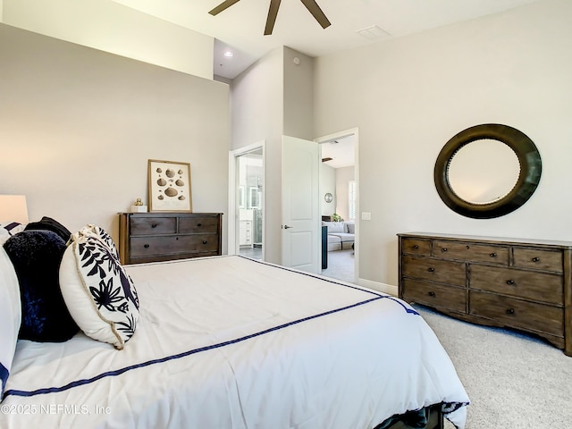 bedroom featuring light carpet, ensuite bath, and ceiling fan