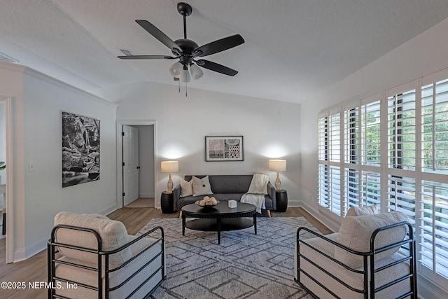 living room with ceiling fan, light hardwood / wood-style floors, and vaulted ceiling