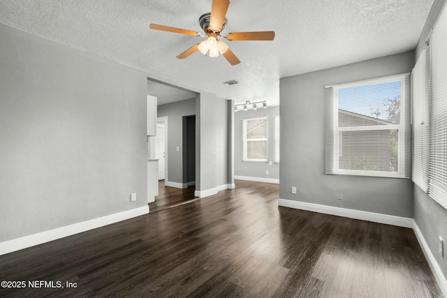 empty room with dark wood-type flooring, a textured ceiling, and ceiling fan