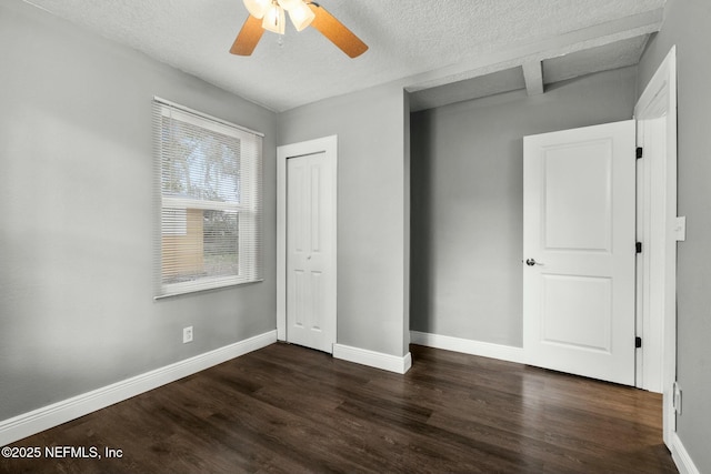 unfurnished bedroom with a closet, a textured ceiling, dark hardwood / wood-style floors, and ceiling fan