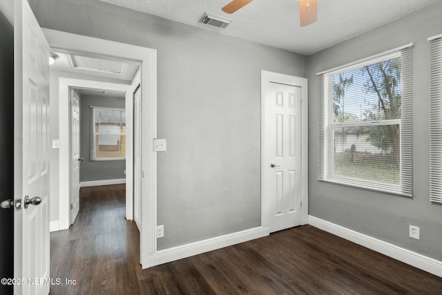 unfurnished bedroom with ceiling fan, dark hardwood / wood-style flooring, a closet, and a textured ceiling