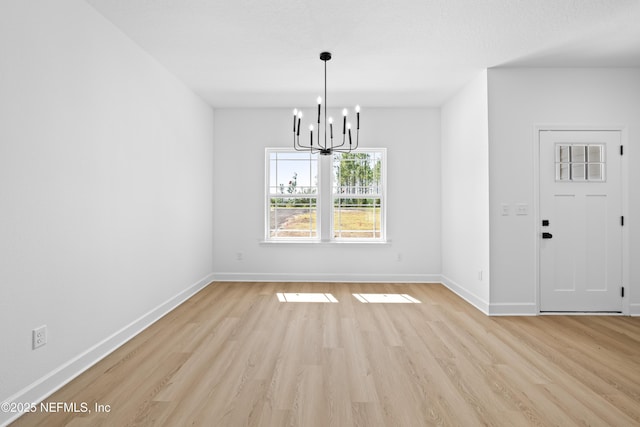 unfurnished dining area with light wood-type flooring and an inviting chandelier