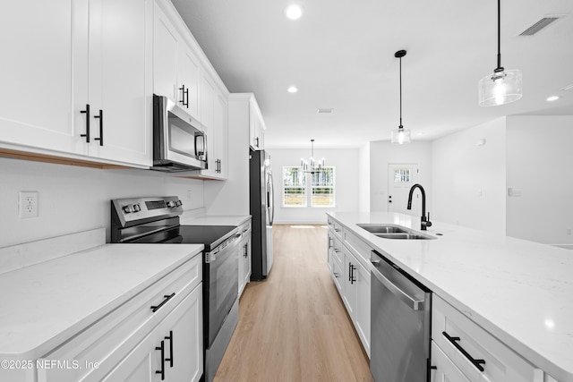 kitchen with pendant lighting, white cabinetry, sink, and stainless steel appliances