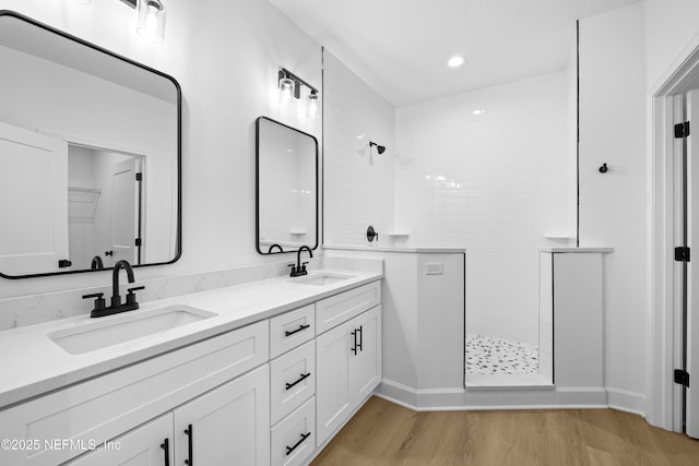 bathroom featuring hardwood / wood-style floors, vanity, and tiled shower