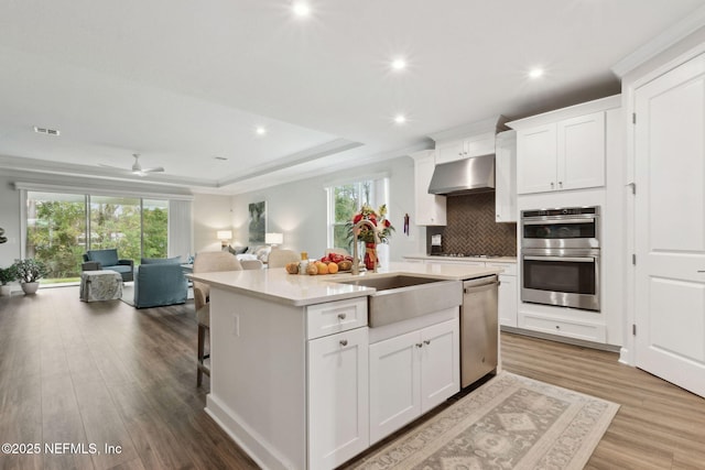 kitchen with a center island with sink, white cabinets, sink, and appliances with stainless steel finishes