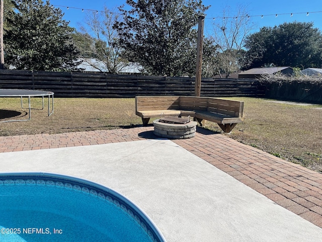 view of swimming pool featuring a patio area, a trampoline, a yard, and an outdoor fire pit