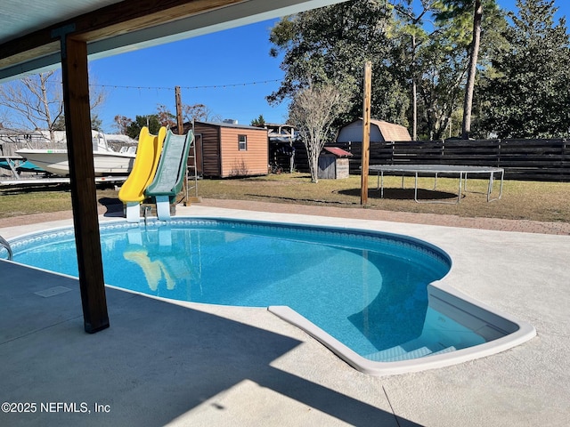 view of pool with a yard, a patio, a shed, and a trampoline