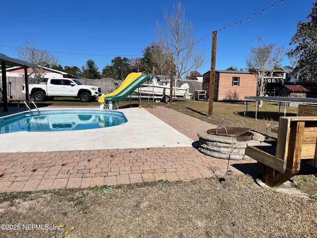 view of pool with a trampoline, a shed, a patio area, a playground, and an outdoor fire pit