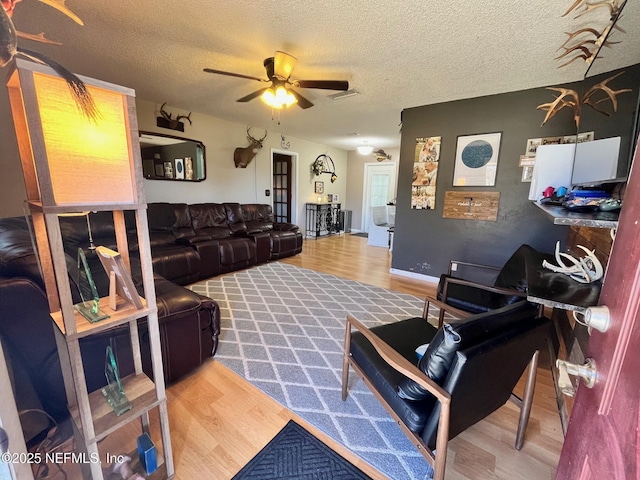 living room with ceiling fan, hardwood / wood-style floors, and a textured ceiling