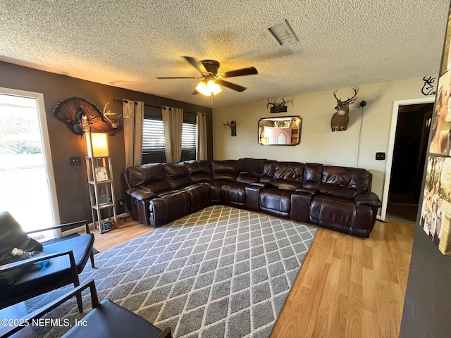 living room featuring hardwood / wood-style floors, ceiling fan, a textured ceiling, and a wealth of natural light