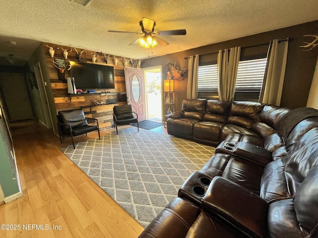 living room featuring ceiling fan, a textured ceiling, and hardwood / wood-style flooring