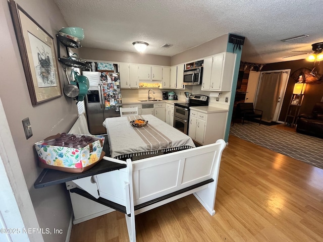 kitchen featuring ceiling fan, sink, a textured ceiling, white cabinets, and appliances with stainless steel finishes