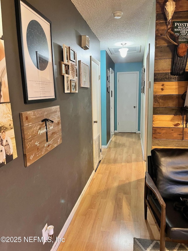 corridor featuring light hardwood / wood-style floors and a textured ceiling