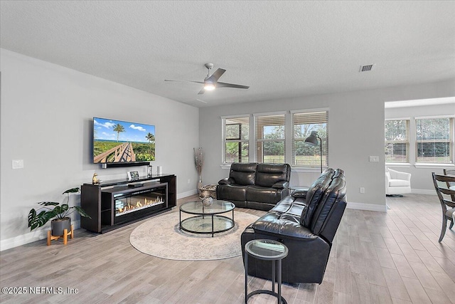 living room featuring a textured ceiling, ceiling fan, and light hardwood / wood-style floors