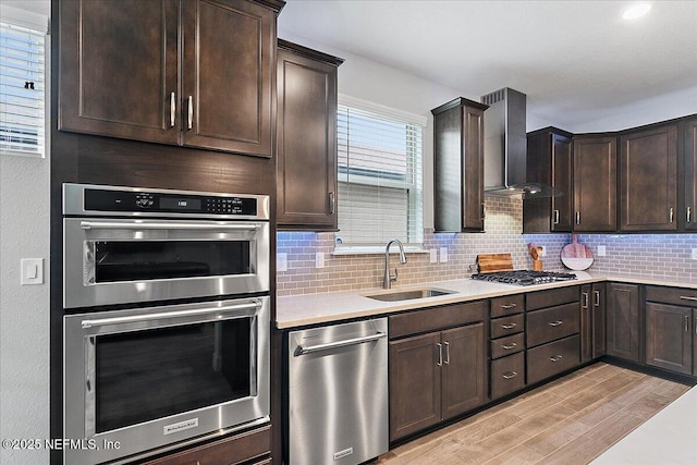 kitchen featuring sink, light hardwood / wood-style flooring, wall chimney exhaust hood, stainless steel appliances, and dark brown cabinets