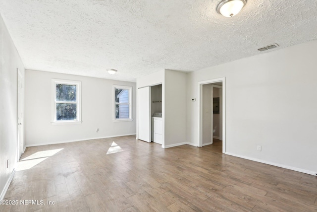 empty room featuring a textured ceiling, dark hardwood / wood-style flooring, and washer / clothes dryer