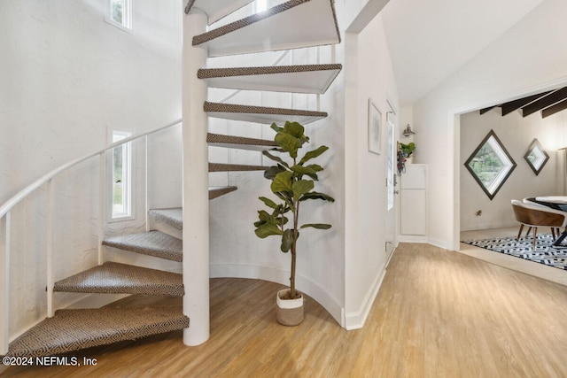 stairway with wood-type flooring and lofted ceiling